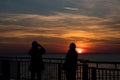 Photo of the sunset with the silhouette of a two ladies.