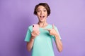 Photo of surprised adorable young lady wear casual teal outfit pointing phone purple color background