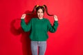 Photo of surprised sweet teen girl dressed green knitted sweater hands arms ponytails isolated red color background Royalty Free Stock Photo