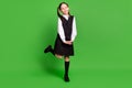 Photo of sweet charming school girl wear black white uniform dancing smiling isolated green color background