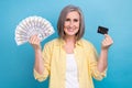 Photo of sweet charming woman dressed yellow shirt rising cash and electronic money isolated blue color background