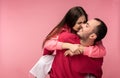 Photo of sweet couple hug each other and smile. Male and female are in love. Woman tries to bite man. Isolated over pink Royalty Free Stock Photo