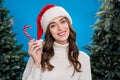 Photo of sweet excited girl dressed santa claus helper hat enjoying sweet x-mas candy cane isolated blue color Royalty Free Stock Photo