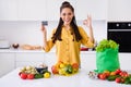 Photo of sweet excited woman dressed yellow shirt buying credit card vegetables showing okey indoors house home room