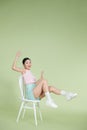 Photo of sweet excited woman smiling rising arms sitting chair isolated on green background Royalty Free Stock Photo