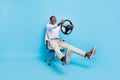 Photo of sweet funky dark skin man wear white shirt smiling sitting chair holding steering wheel isolated blue color Royalty Free Stock Photo