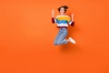 Photo of sweet harsh young woman wear striped sweater jumping showing hard rock sign isolated orange color background Royalty Free Stock Photo