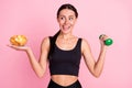 Photo of sweet hungry young lady sportswear holding dumbbell looking potato crisps smiling isolated pink color