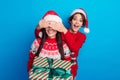 Photo of sweet impressed women santa elves wear ornament pullovers giving x-mas gifts arms cover eyes isolated blue