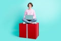 Photo of sweet impressed young lady dressed purple pullover sitting red present writing modern device isolated teal