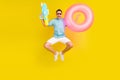 Photo of sweet pretty guy dressed t-shirt dark eyewear smiling jumping holding inflatable rings water gun isolated Royalty Free Stock Photo