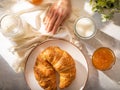 In the photo, the table set for the morning breakfast. Very appetizing croissants, orange jam and coffee with milk. A very