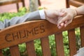 A couple holding hands seated on a wooden bench at Chijmes Gothic style Chapel at Singapore Victoria street