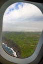 Photo taken out the window of plane, view over island with ocean and clouds Royalty Free Stock Photo