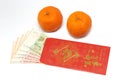 A pair of mandarin oranges and a red envelope with Singapore money notes inside