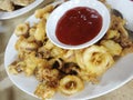 A plate of deep fried cuttlefishes with tomato sauce on a table Royalty Free Stock Photo