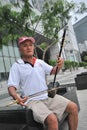 A senior playing a Chinese two-stringed fiddle against the modern city backdrop