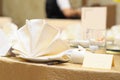 A table setup of beige and milky white tableware, napkins and guest name card at an asian restaurant