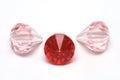 Three ruby red and light pink colored fake diamonds