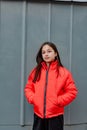 Photo of teenage girl on a grey wall background. Teenager girl in orange jacket