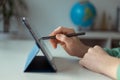 Photo of teens hand tapping with pen on tablet