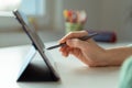 Photo of teens hand tapping with pen on tablet