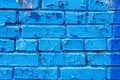 photo of the texture of a brick wall painted with blue paint, the paint is cracked and peeling off in flakes