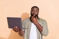 Photo of thinking millennial beard guy hold laptop look up wear grey shirt isolated on beige background Royalty Free Stock Photo