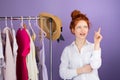 Photo of a thinking redhead young woman in white long sleeve t-shirt she choosing what dress she must buy posing over a Royalty Free Stock Photo