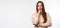 Photo of Thoughtful young woman with long chestnut hair standing with hand raised on chin. Place for ad