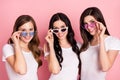 Photo of three attractive young girls happy positive smile hands touch sunglass look sight isolated over pastel color