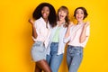 Photo of three delighted pretty girls dark skin fists up open mouth scream yeah isolated on yellow color background