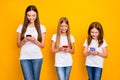 Photo of three funny ladies holding telephones in hands wear casual clothes isolated yellow background