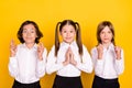 Photo of three hopeful schoolchildren crossed fingers plead wear white shirt isolated yellow color background Royalty Free Stock Photo