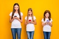 Photo of three ladies holding telephones in hands wear casual clothes isolated yellow background