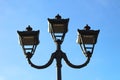 photo of three modern metal LED lamps in vintage style on a single post against a blue sky Royalty Free Stock Photo