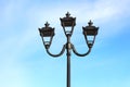 photo of three modern metal LED lamps in vintage style on a single post against a blue sky Royalty Free Stock Photo