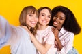 Photo of three pretty positive girls dark skin take selfie put arm on shoulder isolated on yellow color background