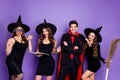 Photo of three witch ladies and wizard guy with broom wand spell book using magic wear black dresses caps suit and long Royalty Free Stock Photo