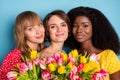Photo of three young girl happy positive smile flowers tulips woman day spring best friends afro isolated over blue