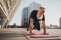 Photo of tired strong old retired man stand plank hand yoga carpet one leg wear t-shirt urban town outdoors