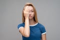 Portrait of tired woman with long chestnut hair in casual red sweater covering her eyes with hand. Weariness and people