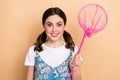 Photo of toothy beaming smile girl young age hobby hunting insects hold pink net wear stylish sarafan isolated on beige Royalty Free Stock Photo