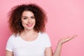 Photo of toothy beaming woman with perming coiffure dressed white t-shirt palm show object empty space isolated on pink