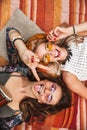 Photo from top of two young hippie girls, smiling and lying on b