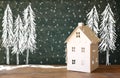 Photo of toy house in front of chalkboard with winter concept drawings