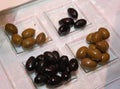 Photo transparent glass dish with four sections, which laid out green and black olives.