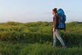 Beautiful traveler woman walking in the meadow with trekking backpack