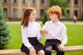 Photo of two best buddies redhead schoolkids sit bench hold little fingers wear white shirt uniform park outdoors Royalty Free Stock Photo