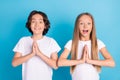 Photo of two cheerful children hold hands plead excited mood wear white t-shirt isolated blue color background